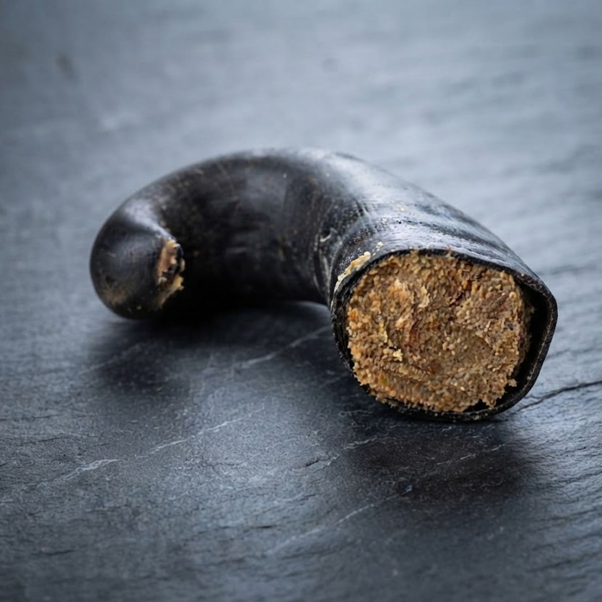 A buffalo horn stuffed with dog pate, on a slate surface