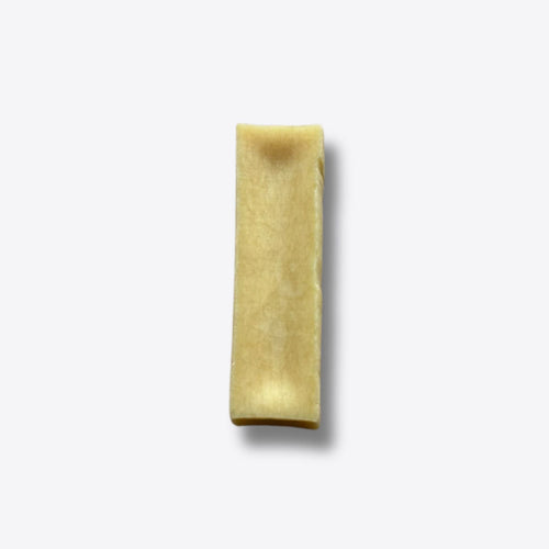 A single plain Himalayan yak chew, a pale hard bar of pressed yak milk, on a white background