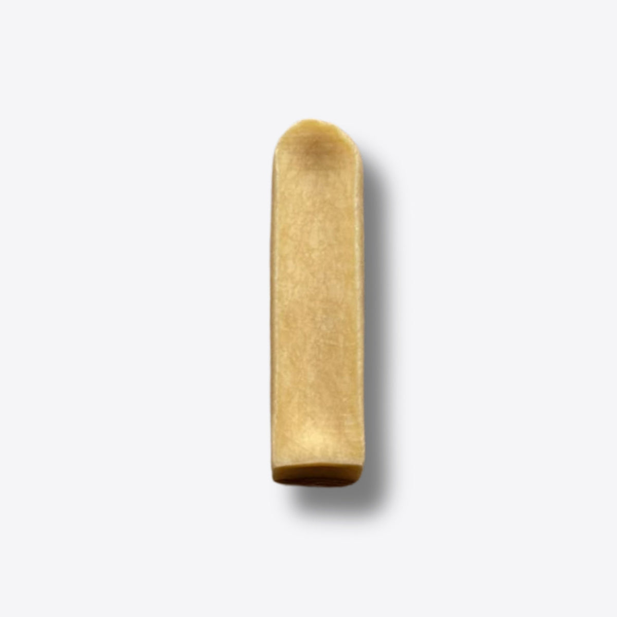 A single mango milk chew, a hard golden bar of pressed milk, on a white background