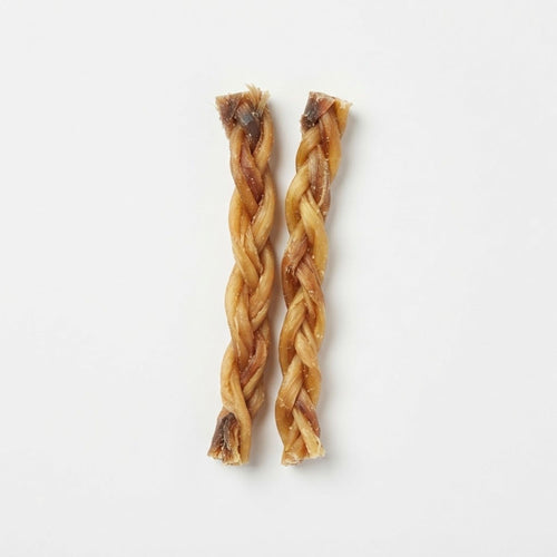 Two natural braided beef tendon chews for dogs on a white background