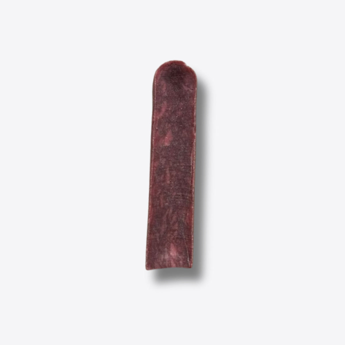 A single cranberry milk chew, a hard deep red bar of pressed milk, on a white background