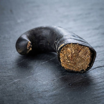 A buffalo horn stuffed with dog pate, on a slate surface