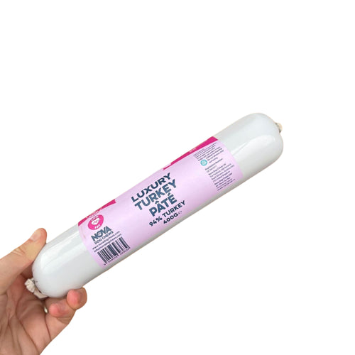 A 400g roll of turkey pate for dogs held in a hand